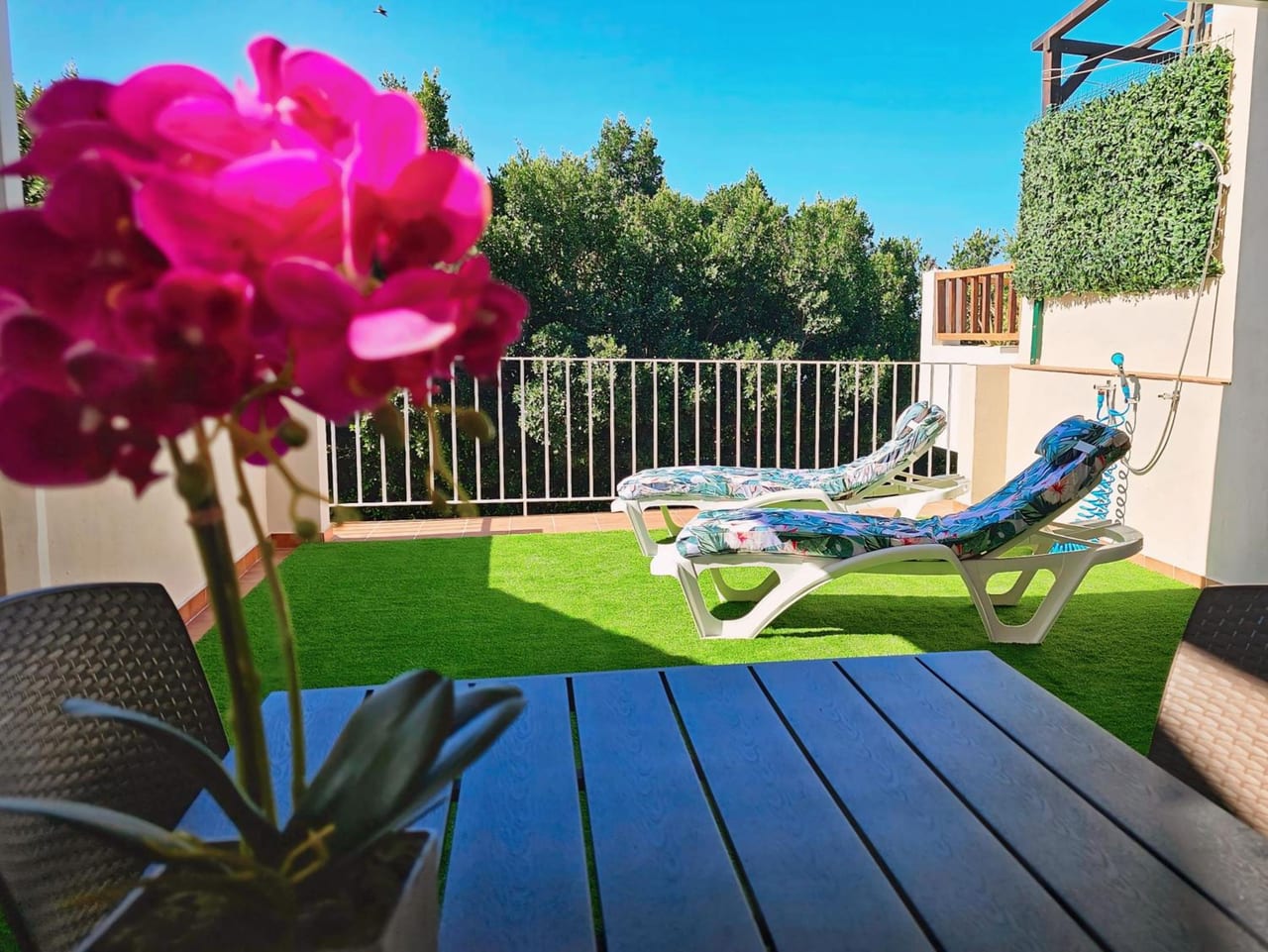 a patio with two chairs and a table with flowers at La casita de Mercedes in Málaga
